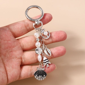 Detail of marine keychain with pearls, silver anchor, seashell and striped fish charms
