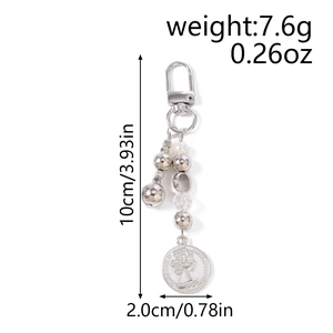 Dettaglio macro del portachiavi a perle argentate con ciondolo moneta Elizabeth II e chiusura