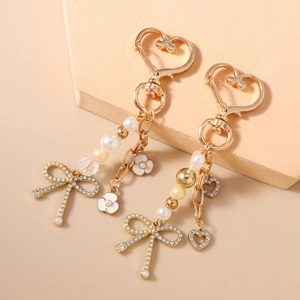 Elegante portachiavi con perle dorate, fiocco di strass e ciondoli a cuore per borse