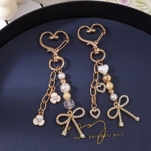 Elegante portachiavi dorato con chiusura a cuore, perle, fiori smaltati e fiocco di strass