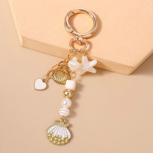 Detail showing the sea shell, starfish charms and pearl beads on the gold keychain