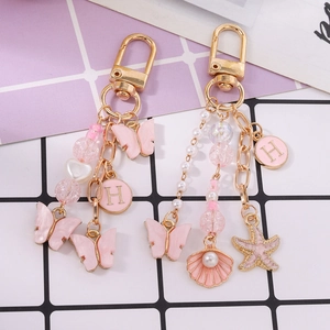 Porte-clés papillon rose avec perles et breloques étoile de mer sur chaîne dorée