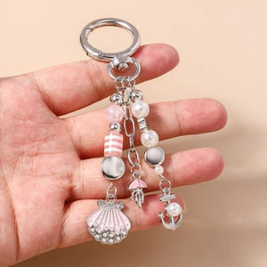 Detail of nautical keychain featuring pink shell, mini jellyfish, and pearls on a spring hook