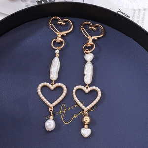 Golden heart-shaped keychain with baroque pearls on a deep blue textured background