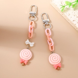 Set of two pink swirl lollipop keychains with bows and colorful plastic chains on stone