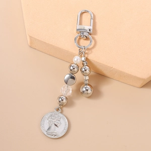 Dettaglio macro del portachiavi in argento con perle, cristalli e pendente a moneta