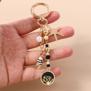 Détail d'un porte-clés nautique doré avec étoile de mer, poisson et pendentif corail