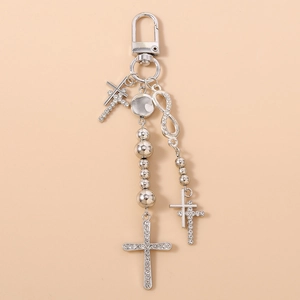 Macro detail of silver keychain featuring rhinestone cross and infinity charms on a lobster clasp