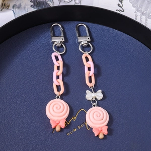 Lollipop keychain set with pink plastic chains and silver metal rings on a blue display plate