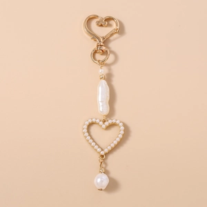 Detailed view of golden heart-shaped hook with baroque pearls and hollow heart charm