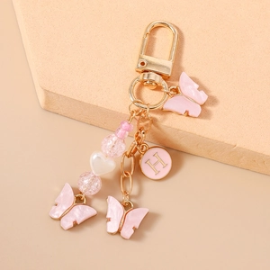Détail du porte-clés papillon en résine rose avec pendentif lettre H dorée