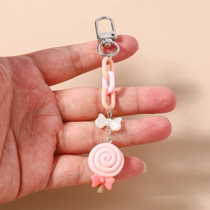 Close-up of pink lollipop keychain with white bow and silver metal spring clasp detail