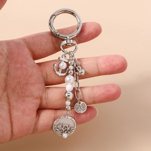 Détail d'un porte-clés en métal argenté avec ancre, perles et pendentif arbre de vie