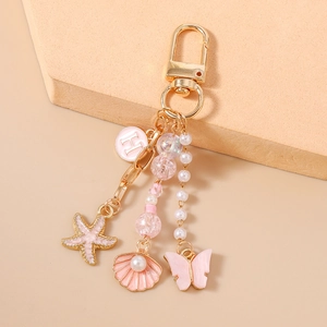 Détails de l'anneau porte-clés doré avec charms d'étoile de mer, coquillage et papillon