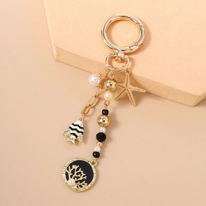 Détail du porte-clés étoile de mer dorée avec charm poisson émaillé et perles blanches