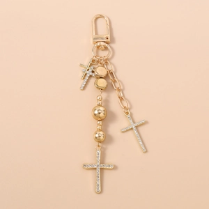Detail of golden beaded keychain with rhinestone-encrusted cross pendants and lobster clasp
