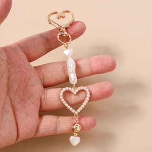 Detailed close-up of beaded heart keychain with baroque pearls and gold plating in hand