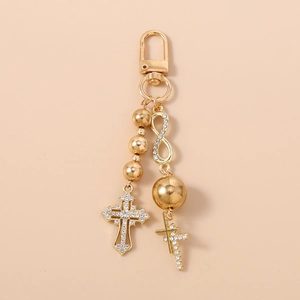 Detail of gold beaded keychain featuring rhinestone cross and infinity symbol charm