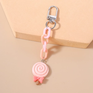 Close-up of pink and orange lollipop keychain with decorative bow on stylish display stone