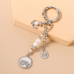 Détails d'un porte-clés argenté avec ancre, perles et pendentif nœud en cristal brillant