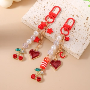 Detailed view of beaded star and cherry heart keychains on white textured stone board