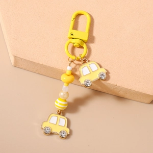 Detail von gelbem Auto-Schlüsselanhänger mit Perlen, Streifen-Charms und Strass-Rädern
