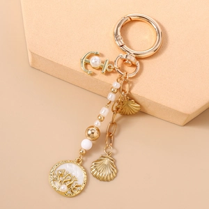 Détail d'un porte-clés nautique avec ancre dorée, coquillages et perles élégantes