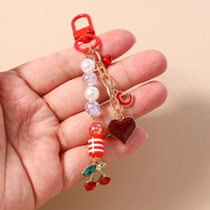 Close-up of beaded cherry and heart keychain with red metal clip and glitter heart charm