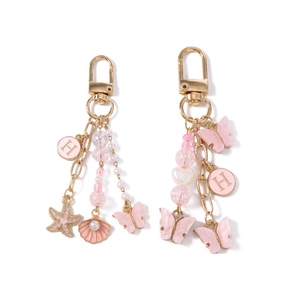 Porte-clés coquillage perle étoile de mer rose doré avec breloque H et aile de papillon
