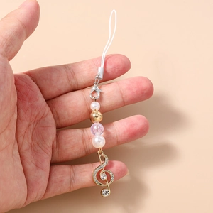 Detail of music note phone charm with pearls, rhinestones and golden G-clef pendant