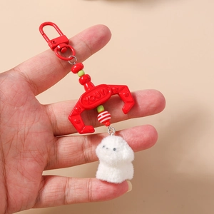 Detail of red claw machine hook keychain with fluffy white plush puppy dog and beads