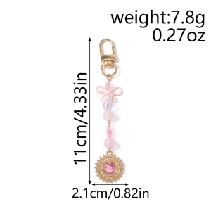 Vue détaillée du porte-clés à nœud rose avec chaîne perlée et pendentifs soleil strass