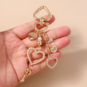 Dettaglio portachiavi dorato con perle, strass e ciondolo a cuore con incisione Love You