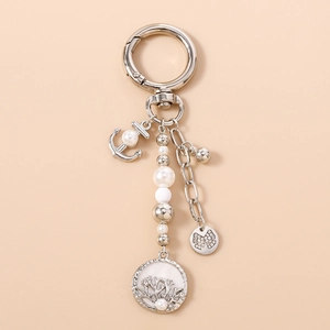 Détail du porte-clés ancre argentée avec perles blanches et pendentif arbre de vie