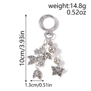 Detail of silver keychain with metal leaf, butterfly pendants, and dimension markings