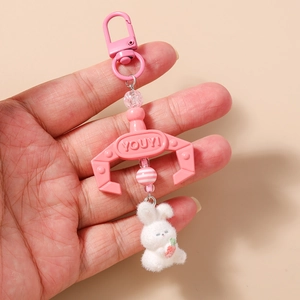 Detailed close-up of a plush white bunny and pink plastic claw keychain handheld view