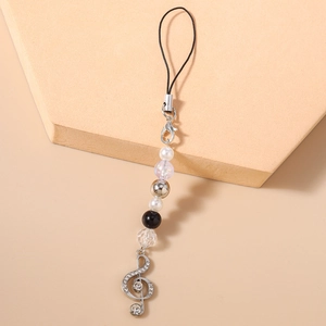 Detailed view of silver treble clef phone charm with rhinestones and white pearls