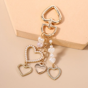Dettaglio portachiavi a cuore dorato con perle, strass e ciondolo inciso Love You