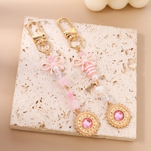 Porte-clés avec nœud rose, perles et médaillon solaire doré orné d'un grand cristal