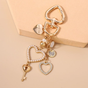 Dettaglio di un portachiavi a cuore dorato con strass, perle e incisione Love You