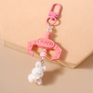 Close-up of pink doll catcher claw and white plush rabbit keychain accessory