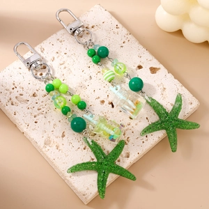 Porte-clés étoile de mer verte avec perles rayées et charme bouteille sur pierre