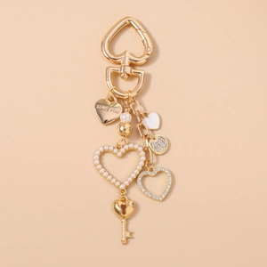 Dettaglio del portachiavi dorato a forma di cuore con incisione LOVE YOU e perle