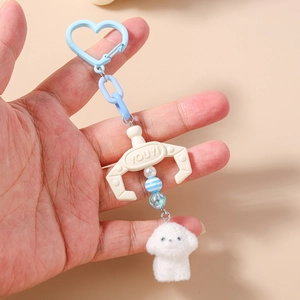 Detail of blue plush dog keychain with a white claw machine claw and heart-shaped clasp