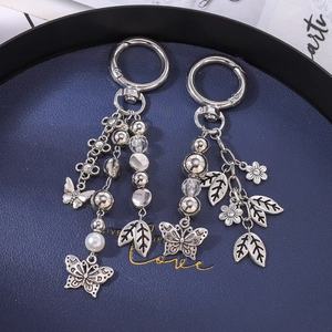 Vintage silver metal keychain with butterfly and leaf charms on a dark tray