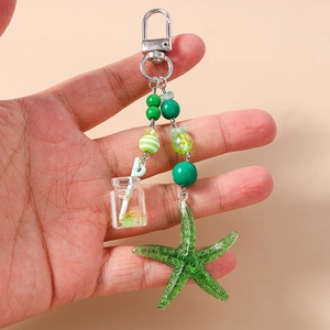 Vue détaillée d'une étoile de mer en résine verte et d'un pendentif en bouteille