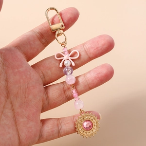 Détail d'un porte-clés à perles roses avec un nœud et un pendentif tournesol doré strassé