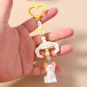 Detail view of plush puppy keychain with yellow heart clasp, plastic chain and white claw