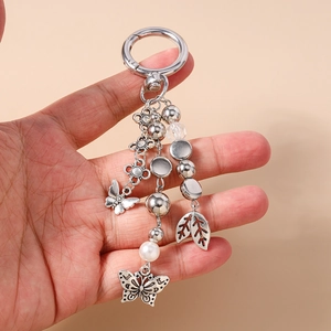 Detail view of retro silver keychain with butterfly, leaf charms and white faux pearl