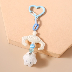 Close-up of plush puppy keychain with heart hook and miniature plastic claw detail